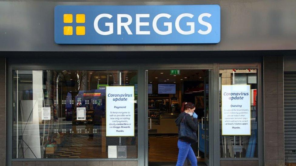 Woman wearing mask walks past Greggs shop