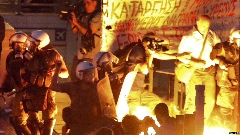 Rot police stand among the flames from exploded petrol bombs thrown by anti-austerity demonstrators in front of parliament in Athens (15 July 2015)