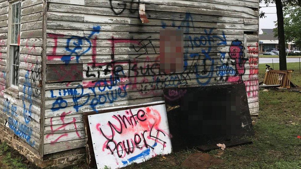 Graffiti covers one side of the historical Ashburn old school - signs read "white power" "life sucks" and there are several swastikas.