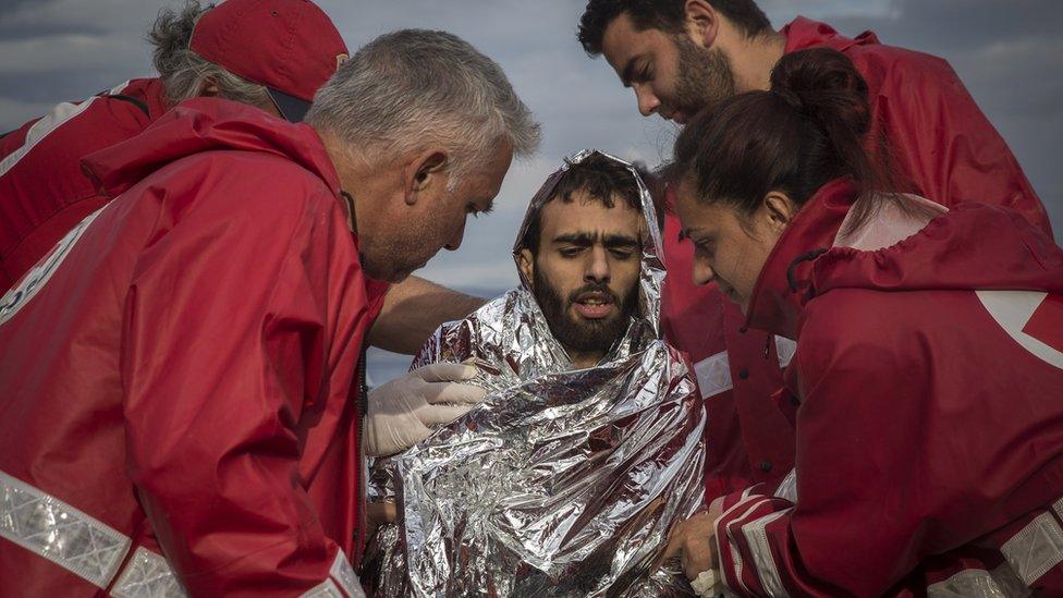 Members of the Greek Red Cross help a man who arrived on a dinghy from the Turkish coast on the Greek island of Lesbos