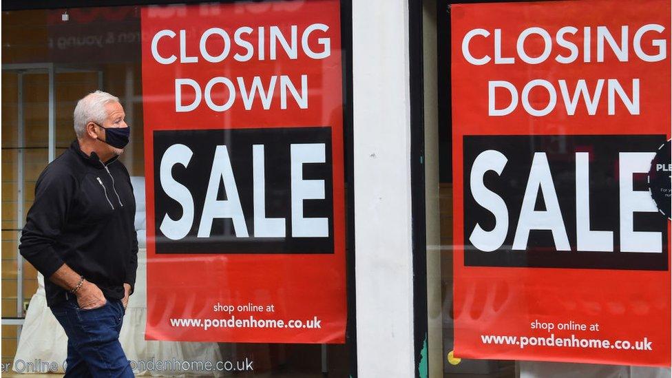 Man walking past a shop that is closing down