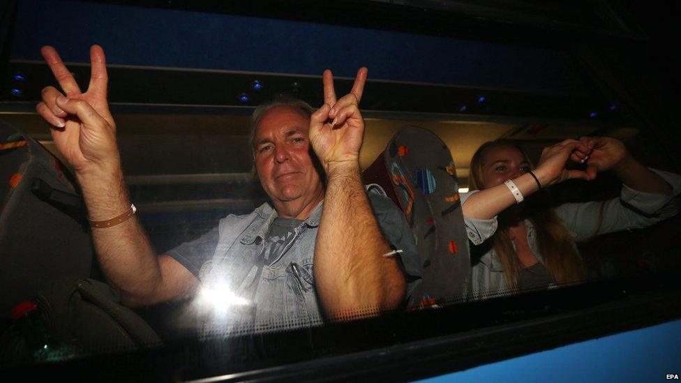 Tourists gesture peace signs from inside a bus as demonstrators take part in a rally in front of the Hotel Imperial Marhaba in Sousse, Tunisia, 28 June 2015