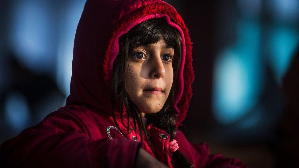 A migrant girl from Afghanistan looks on in a barrack in a refugee camp near Belgrade on 21 January 2017