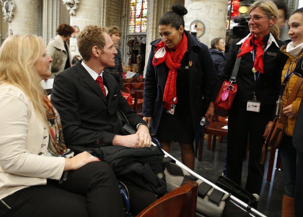 Airport worker Geoffroy Lemaitre, who was injured in the bombing, talks to fellow airport workers prior to the start of an ecumenical service for the victims of the Brussels bomb attacks at the Cathedral of St Michael and St Gudula in Brussels, 28 March