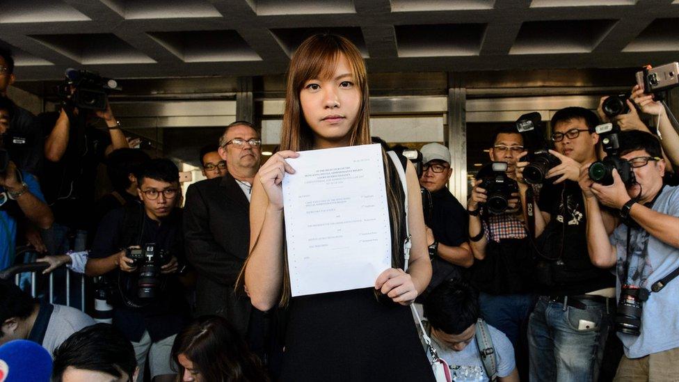 Pro-independence lawmaker Yau Wai-ching (C) holds a court ruling as she leaves the High Court in Hong Kong on November 15, 2016