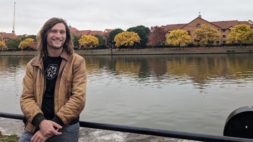 Man sits on railing beside river