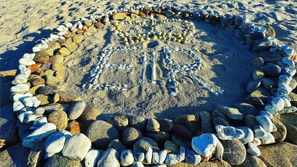 'ER' circled and written in beach stones