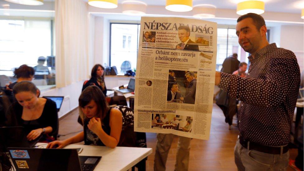 Nepszabadsag journalists paste a copy of the last issue onto the wall of a temporary newsroom in Budapest