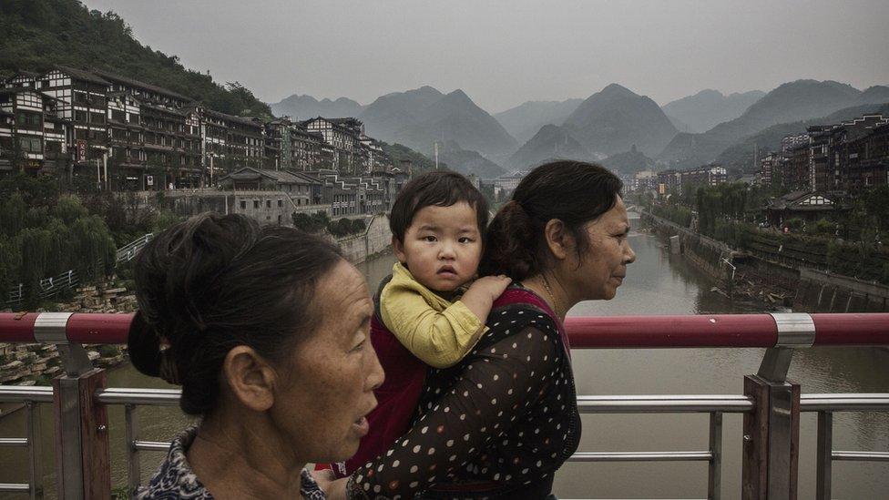 A Chinese woman carries a child across a bridge over the Chishui River