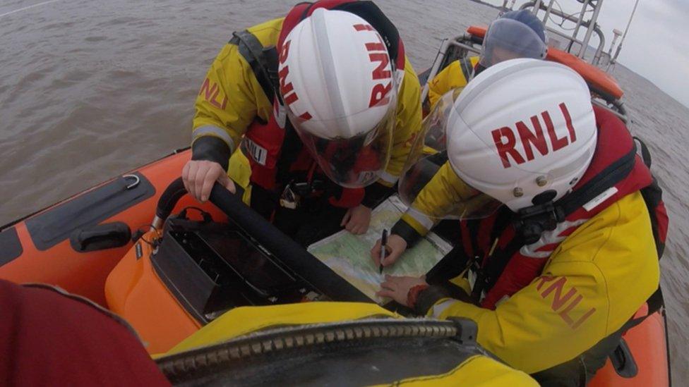 Two RNLI volunteers sat in a lifeboat looking at some assessment paperwork