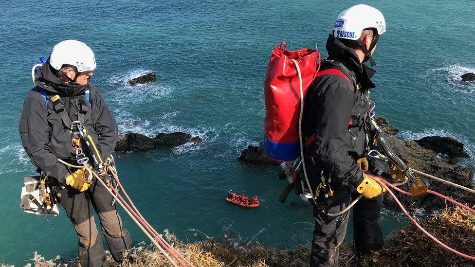 Two rope climbers stating their descent from the top of the cliff