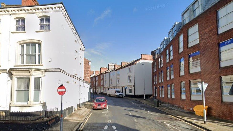 Town centre street showing four-storey brick-built building on the right