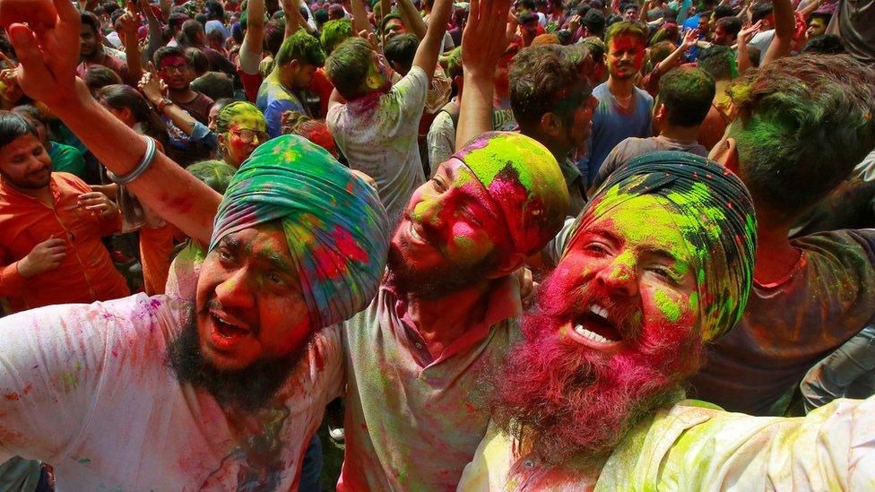 Students with their faces smeared in colourful powder dance