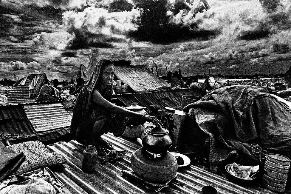 Woman cooking on rooftop, Jinjira, Dhaka, Bangladesh. 1988.