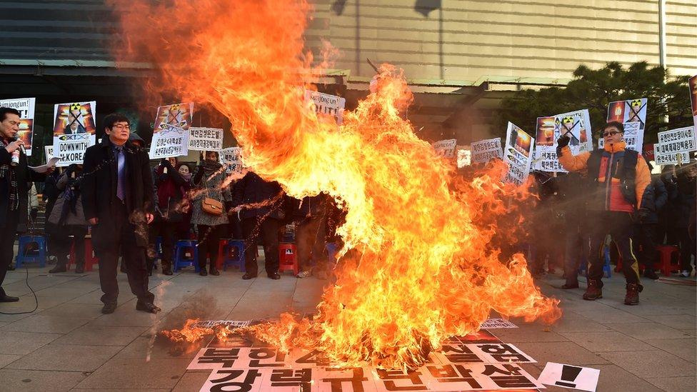 Protesters in South Korea standing around a large fire, demonstrating against North Korea's nuclear test