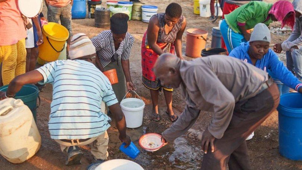 People fetch water at a burst pipe during Zimbabwe's presidential and legislative elections in Bulawayo on August 23, 2023