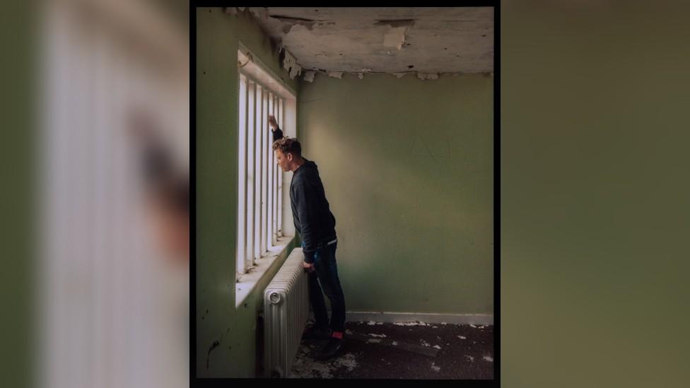 Danny stands in a cell block of his former prison