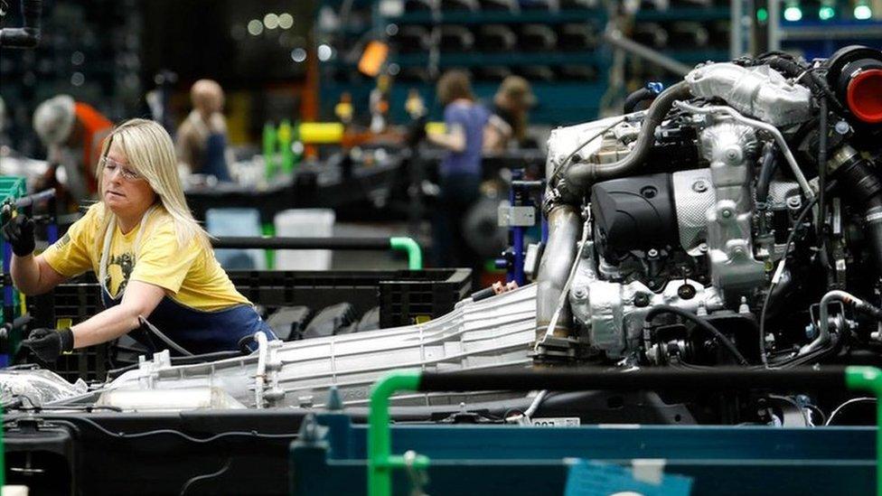 line workers work on the chassis of full-size General Motors pickup trucks