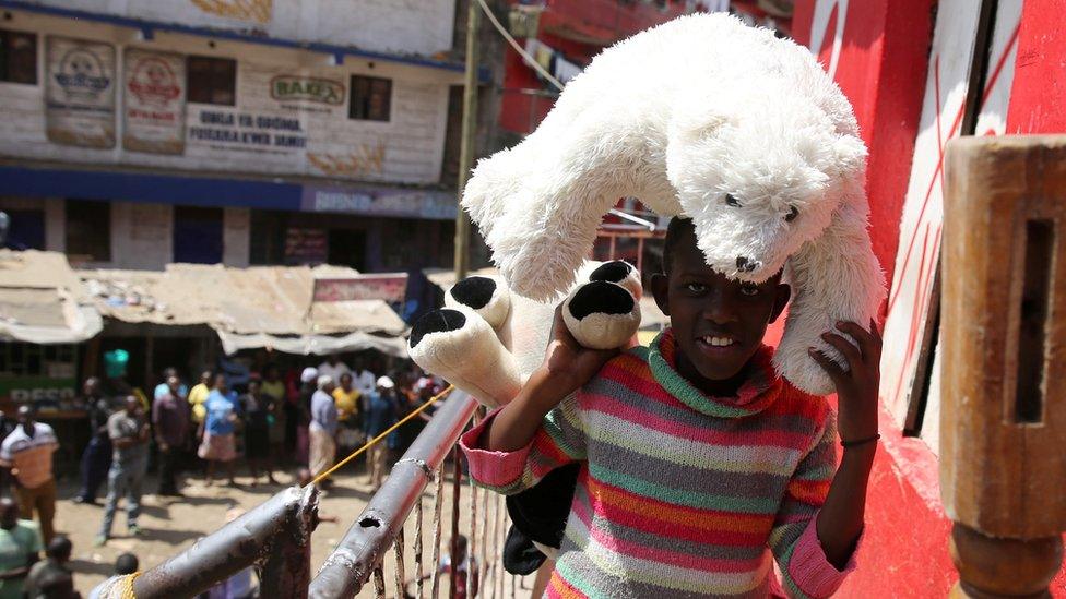 A girl carries her teddy bear out of a building earmarked for demolition in the Mathare neighbourhood of Nairobi, Kenya, May 17, 2016