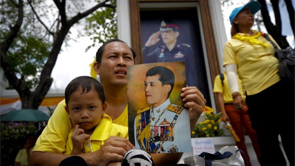 Thai man with a young child holds a portrait of Thai King Maha Vajiralongkorn Bodindradebayavarangkun during the coronation ceremony on a large screen outside the Grand Palace in Bangkok, Thailand, 04 May 2019