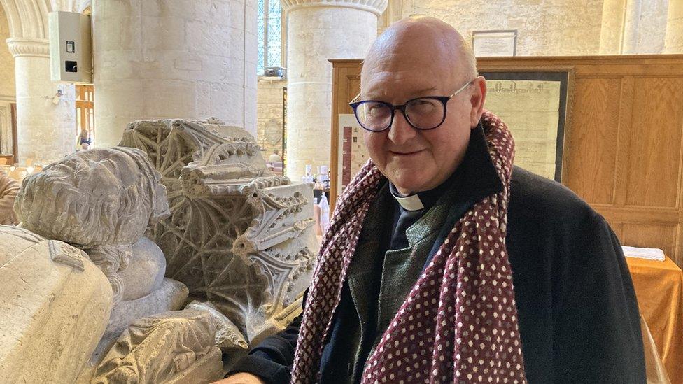 The Reverend Oliver Ross stands in the abbey next to the medieval reconstruction of the empty tomb of King Athelstan.