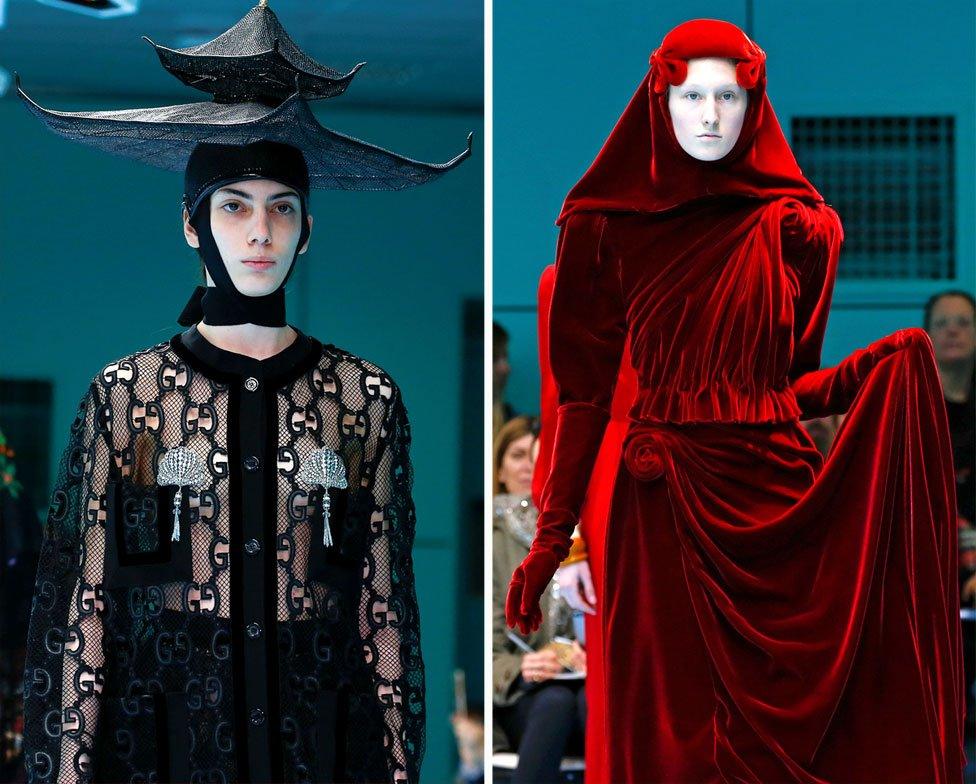 Two models on the catwalk, one wearing a black top with a black hat in the shape of tiered building, the other wearing a red velvet dress including a red headscarf