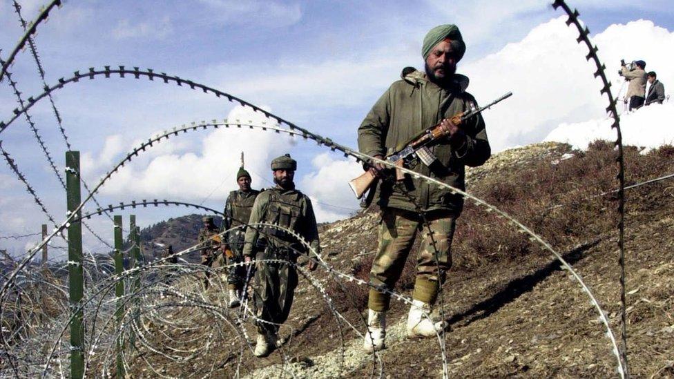 Armed Indian soldiers patrolling along a barbed-wire fence, on the Line of Control between Pakistan and India, 2003