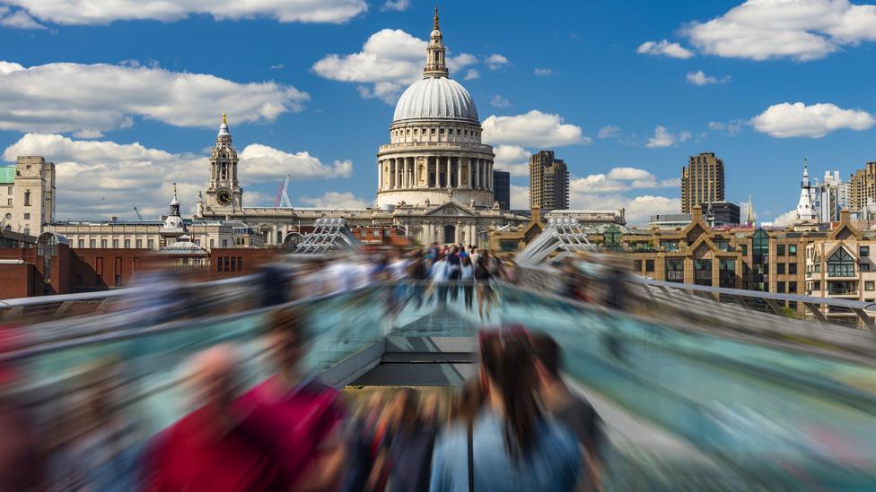 Time-lapse image depicting pedestrians in motion on the Millennium Bridge