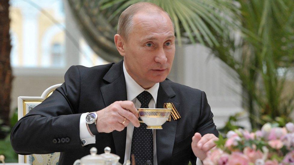 Vladimir Putin lifting a cup of coffee with his watch visible on the right hand