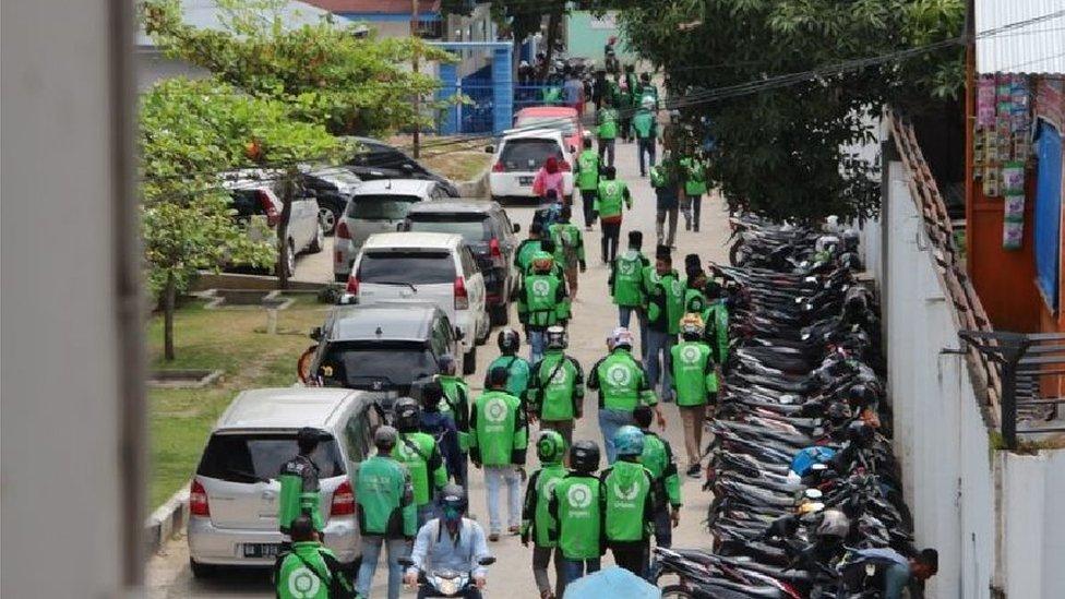 The motorcycle taxi drivers walking towards the hospital