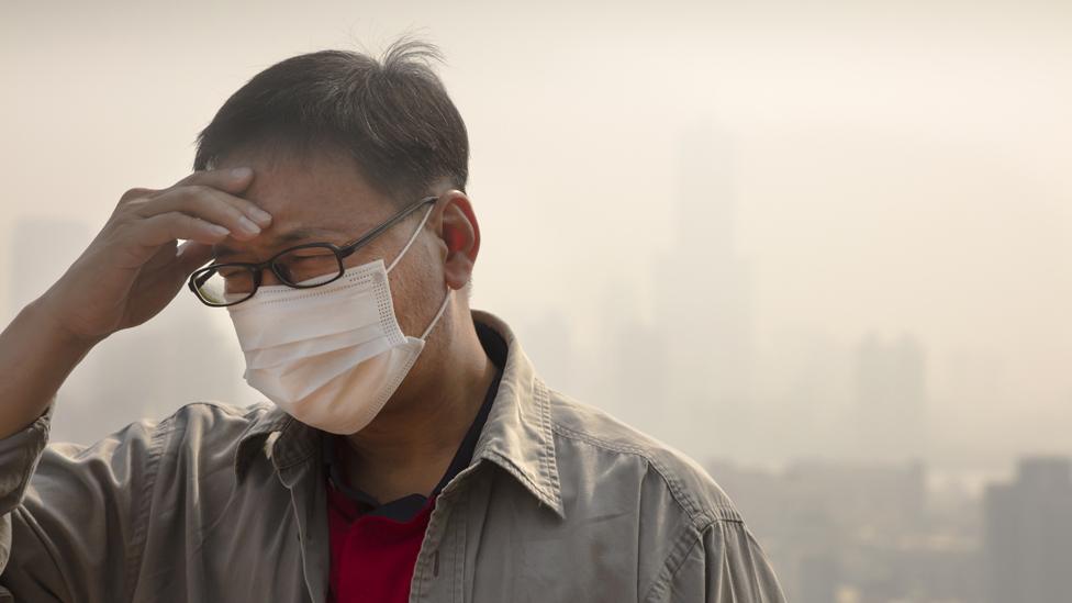 Man in mask in smog-filled city