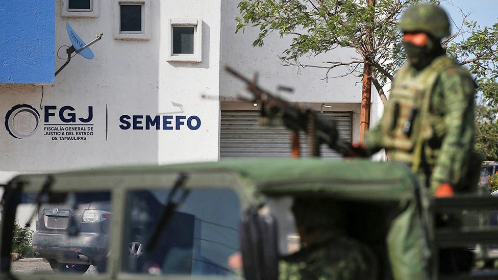 Troops stand guard at the morgue where the Americans' bodies were taken