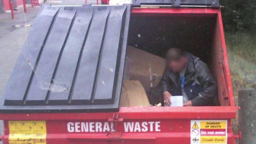 Homeless man sitting inside Biffa recycling bin