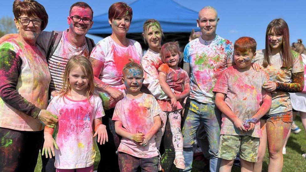 Five adults and five children, covered in coloured powder