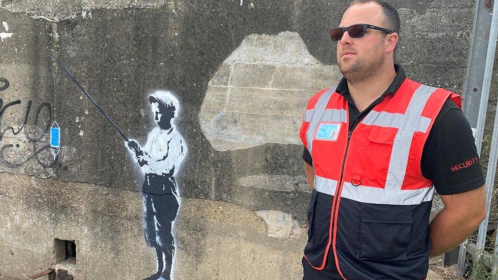 A security guard protecting a mural in Harwich