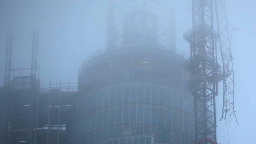 Fog surrounds a damaged crane attached to St Georges Wharf Tower after a helicopter reportedly collided with it
