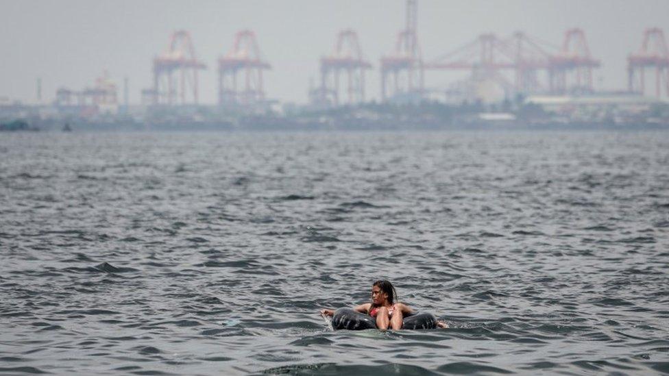 A woman floats on an inner tube of a rubber wheel on Easter Sunday at Manila Bay, Pasay City, south of Manila, Philippines, 01 April 2018