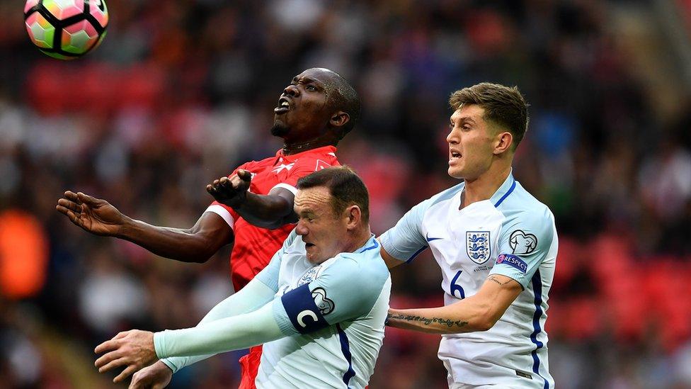 Wayne Rooney and John stones trying to head a football