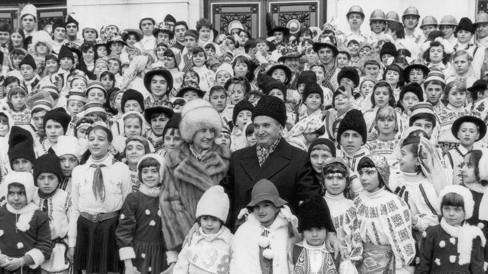 Romanian communist leader Nicolae Ceausescu pictured in around 1985 with his wife Elena and a large group of children in national costume.