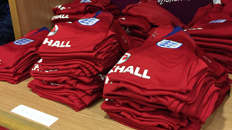 A pile of England training tops on a workbench