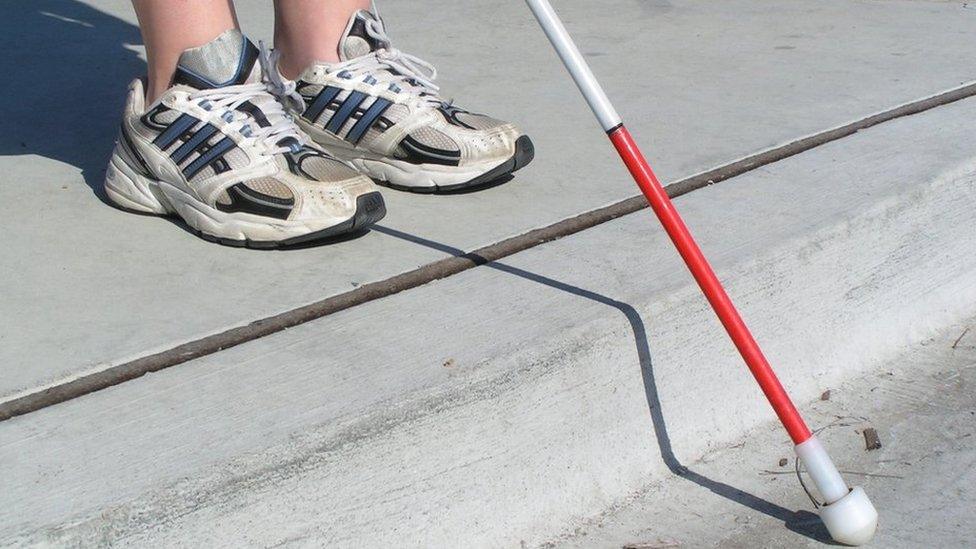 White cane over a road kerb