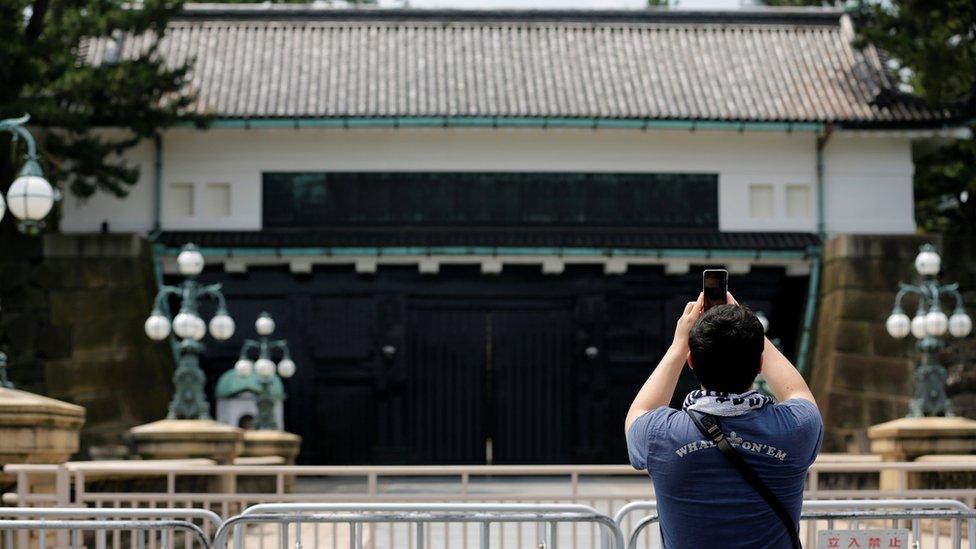 A man takes a photo at the Imperial Palace in Tokyo