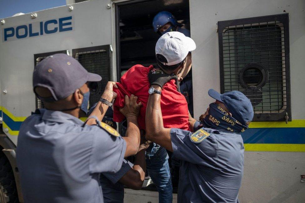 South African Police Service officers force a student member of the Economic Freedom Fighters inside a police van during a protest in Braamfontein, Johannesburg on 10 March 2021.