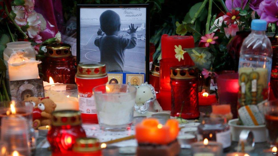 Portrait of 10-month-old Darina Gromova next to flowers and candles at Pulkovo airport near St Petersburg, 2 November 2015