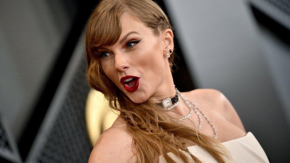 taylor swift on the grammys red carpet looking happy and surprised