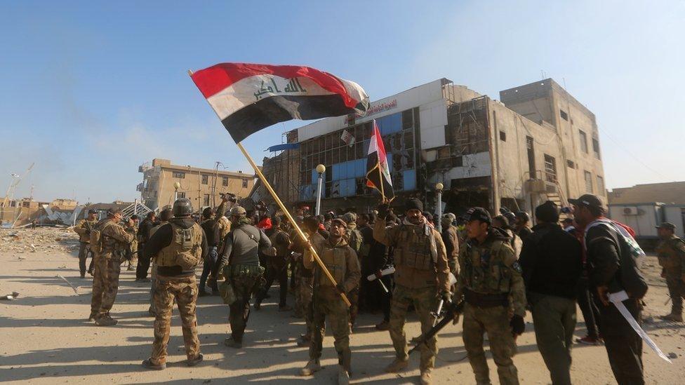 Iraqi security forces wave their national flag in December 2015 in front of the Anbar police headquarters, after their recapture of the city of Ramadi from IS