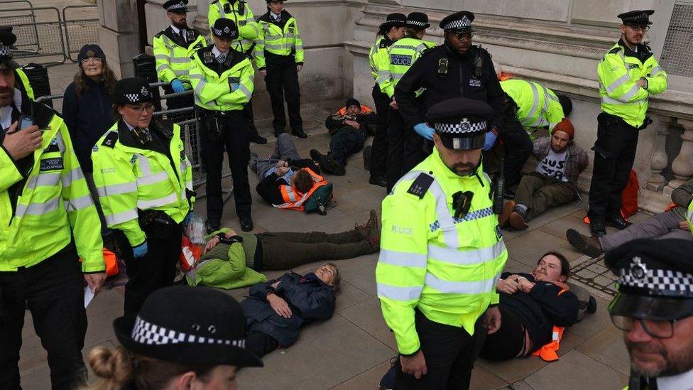 Police officers stand with Just Stop Oil activists after they were detained after taking part in a slow march near Whitehall