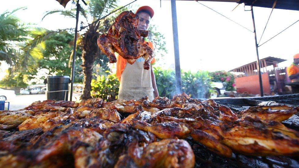 A man holding up a grilled chicken in Tafara, Zimbabwe - Saturday 2 April 2016