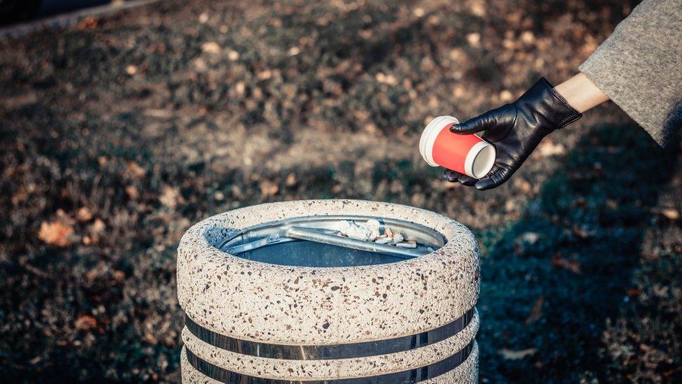 woman putting paper cup into bin