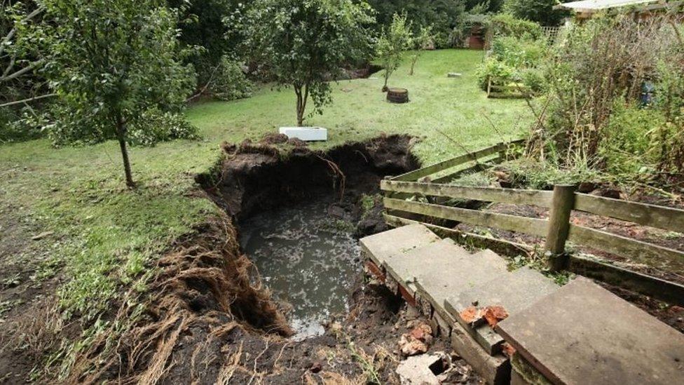 A sink hole in a garden after heavy rain.